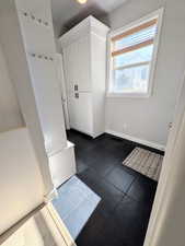 Mudroom featuring baseboards and dark tile patterned floors