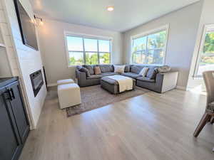 Living room with plenty of natural light, light wood finished floors, recessed lighting, and a fireplace