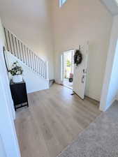 Foyer featuring light wood finished floors, stairway, and a high ceiling