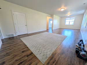 Spare room featuring baseboards and dark wood-style floors