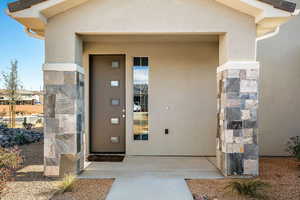 Doorway to property featuring stucco siding, a porch, and stone siding