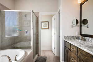 Full bath with vanity, a stall shower, a garden tub, and light wood-type flooring