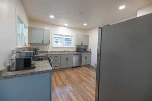 Kitchen featuring gray cabinetry, appliances with stainless steel finishes, healthy amount of natural light, dark wood finished floors, and recessed lighting