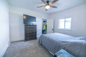 Bedroom with carpet, a walk in closet, and ceiling fan