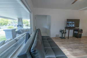 Living area with light wood-type flooring, ceiling fan, and arched walkways