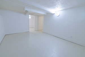 Below grade area with a textured ceiling and baseboards