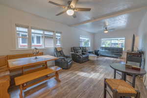 Living room featuring wood finished floors, ceiling fan, a textured ceiling, and beamed ceiling