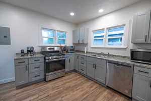 Kitchen featuring gray cabinetry, appliances with stainless steel finishes, electric panel, dark wood-style floors, and recessed lighting