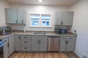 Kitchen with gray cabinets, appliances with stainless steel finishes, wood finished floors, and recessed lighting