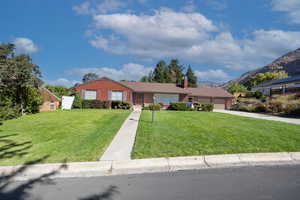 Ranch-style house featuring a front lawn, concrete driveway, a garage, a chimney, and brick siding