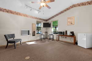 Living area featuring vaulted ceiling, carpet flooring, rail lighting, an office area, and a ceiling fan
