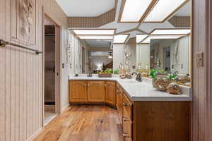 Full bath featuring light wood-type flooring, double vanity, wallpapered walls, a stall shower, and ceiling fan