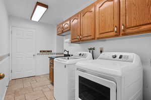 Laundry room with wainscoting, stone tile floors, cabinet space, and separate washer and dryer