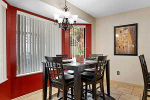 Dining room featuring a chandelier, stone tile floors, and a textured wall