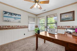 Carpeted office space with wainscoting, ornamental molding, ceiling fan, a textured ceiling, and wooden walls