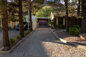 View of home's exterior featuring brick siding, driveway, a gate, and a carport
