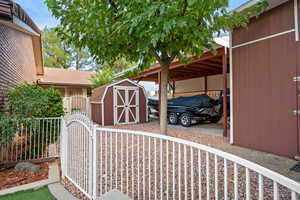 View of home's exterior featuring a storage unit and a gate