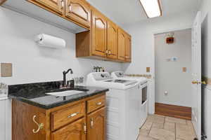 Laundry room with cabinet space, stone tile flooring, and independent washer and dryer