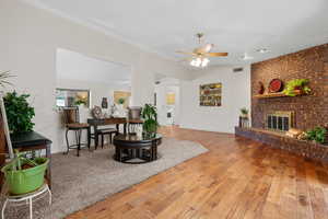 Living room featuring a ceiling fan, a fireplace, and light wood finished floors