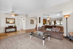 Living area with ceiling fan, light carpet, and light tile patterned floors
