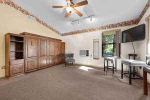 Living area featuring light colored carpet, lofted ceiling, track lighting, and ceiling fan