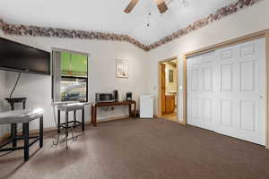 Sitting room with ceiling fan, vaulted ceiling, and carpet flooring