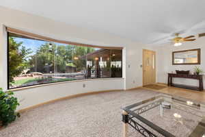 Unfurnished living room featuring ceiling fan and carpet floors