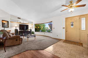 Living room featuring vaulted ceiling, a textured ceiling, ceiling fan, and light wood finished floors