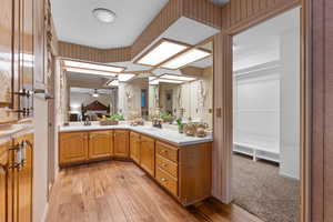 Ensuite bathroom featuring double vanity and light wood-type flooring
