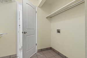 Washroom with light tile patterned flooring and hookup for a washing machine