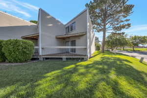 Back of house featuring a lawn and a deck