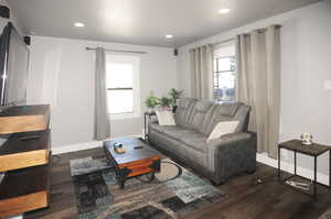 Living room with dark wood finished floors and recessed lighting