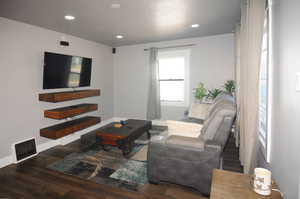 Living room featuring dark wood-type flooring, recessed lighting, and a textured ceiling