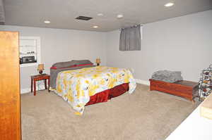 Bedroom with carpet, a textured ceiling, and recessed lighting
