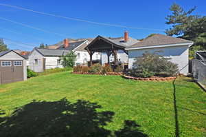 Rear view of property with concrete block siding, a shingled roof, a shed, and a patio area