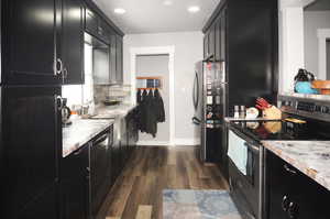 Kitchen with dark cabinets, stainless steel appliances, dark wood-type flooring, light countertops, and recessed lighting