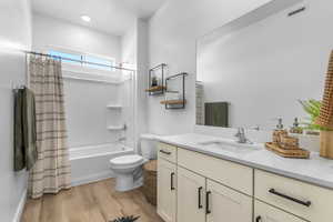 Bathroom featuring shower / bathtub combination with curtain, vanity, and light wood-style floors
