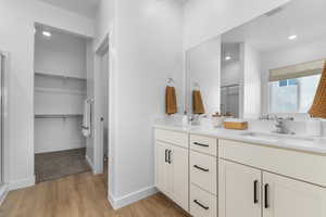 Full bath featuring double vanity, a shower stall, light wood-style floors, recessed lighting, and a walk in closet