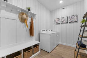 Washroom featuring light wood-type flooring, washing machine and dryer, and recessed lighting