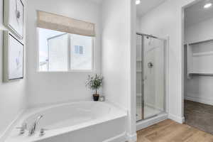 Full bathroom with a stall shower, a bath, light wood finished floors, and a spacious closet