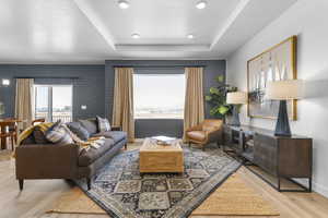 Living area featuring a raised ceiling, light wood-type flooring, and recessed lighting