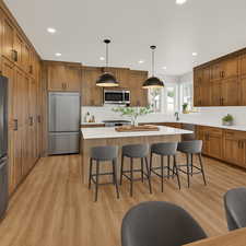 Kitchen featuring brown cabinetry, pendant lighting, a breakfast bar area, stainless steel appliances, and recessed lighting