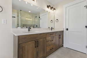 Full bath featuring double vanity, a stall shower, and light tile patterned floors