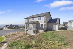 Back of property featuring stucco siding, roof with shingles, a patio area, and a balcony