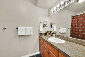 Full bathroom with vanity, a shower with shower curtain, and dark tile patterned flooring