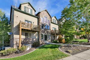 Back of property with stone siding and a lawn