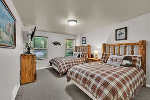 Carpeted bedroom featuring a textured ceiling and baseboards
