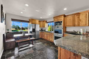 Kitchen featuring stainless steel appliances, recessed lighting, stone tile flooring, and brown cabinetry