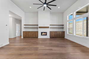 Unfurnished living room with a glass covered fireplace, dark wood-style flooring, recessed lighting, and ceiling fan