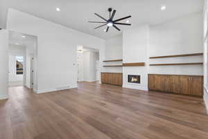 Unfurnished living room with recessed lighting, a glass covered fireplace, wood finished floors, and ceiling fan